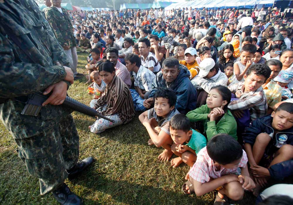 A Thai official stands guard as refugees from members of the Karen ethnic minority from Myanmar sit at the Thai-Myanmar border town of Mae Sot. Photo: Reuters