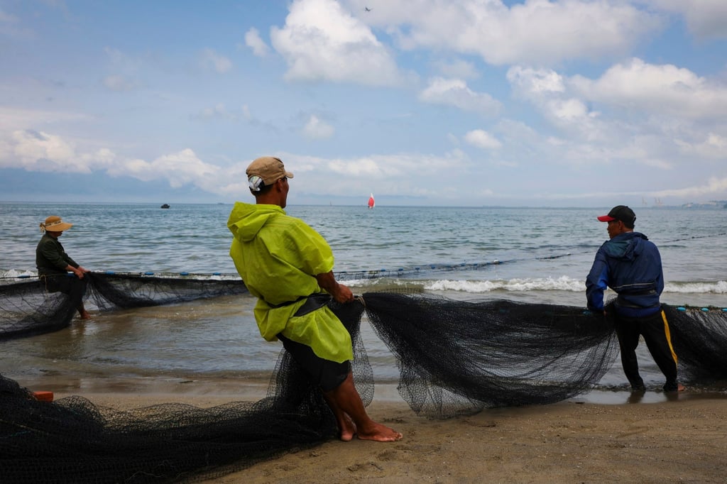 Fishermen on a beach in Da Nang, Vietnam, haul in a net. Warming seas are affecting fish stocks. Photo: AP Fishermen on a beach in Da Nang, Vietnam, haul in a net. Warming seas are affecting fish stocks. Photo: AP