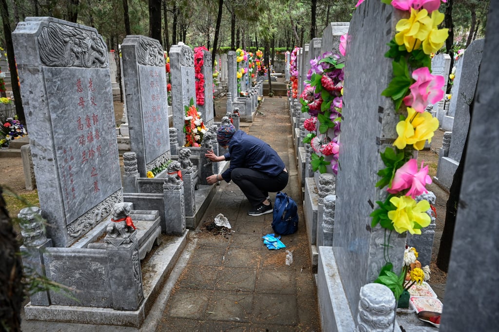 A woman sweeps a tomb during Ching Ming at Babaoshan Cemetery in Beijing. Photo: AFP