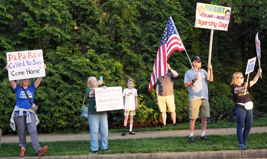 Protesters stand on the side of the road as the motorcade carrying President Donald Trump nears Trump National Golf Club in Washington DC on Thursday. Photo: AP Protesters stand on the side of the road as the motorcade carrying President Donald Trump nears Trump National Golf Club in Washington DC on Thursday. Photo: AP