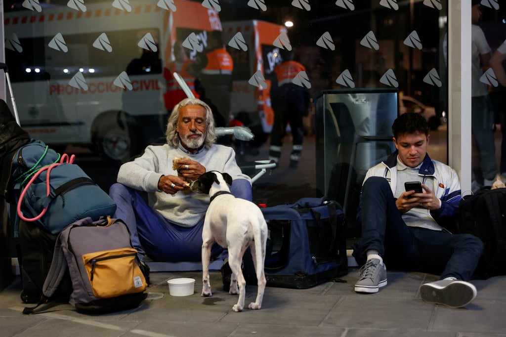 People with luggage sit on the floor at Joaquin Sorolla railway station, as a power outage hit large parts of Spain. Photo: Reuters
