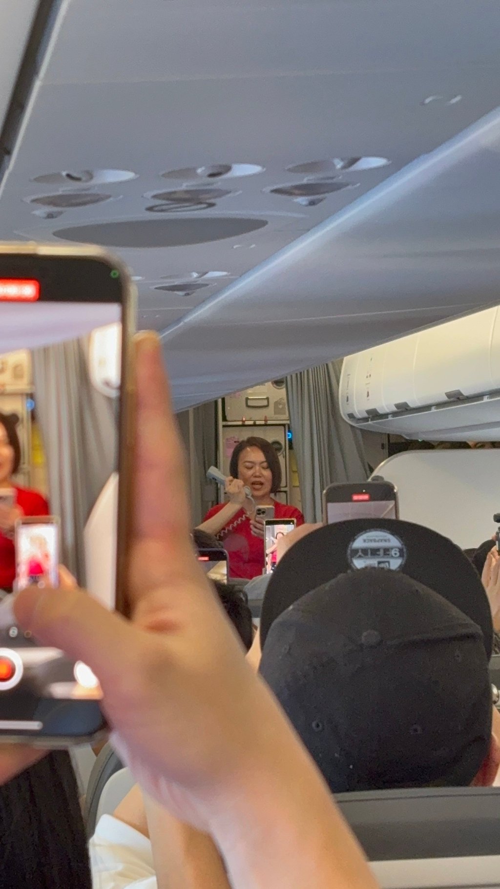 HK Express passengers take videos as a Tam Jai “jehjeh” announces the availability of the restaurant chain’s instant noodles on the in-flight menu. Photo: Erika Na