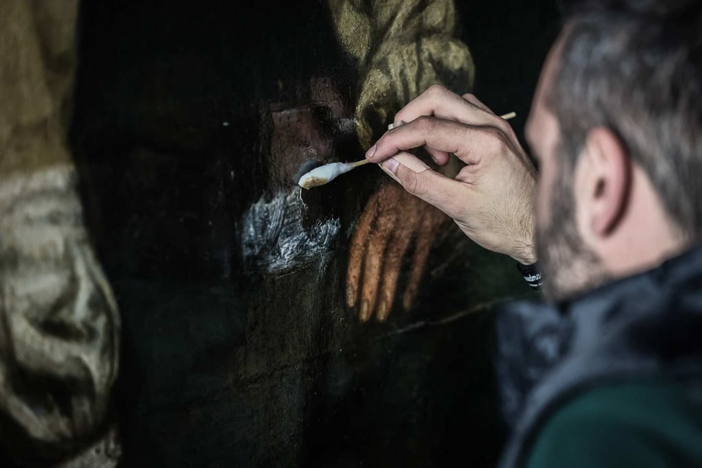 An art restorer carefully removes layers of varnish that have yellowed over time as he works on Gustave Courbet’s painting titled A Burial at Ornans at the Orsay Museum in Paris. Photo: AFP