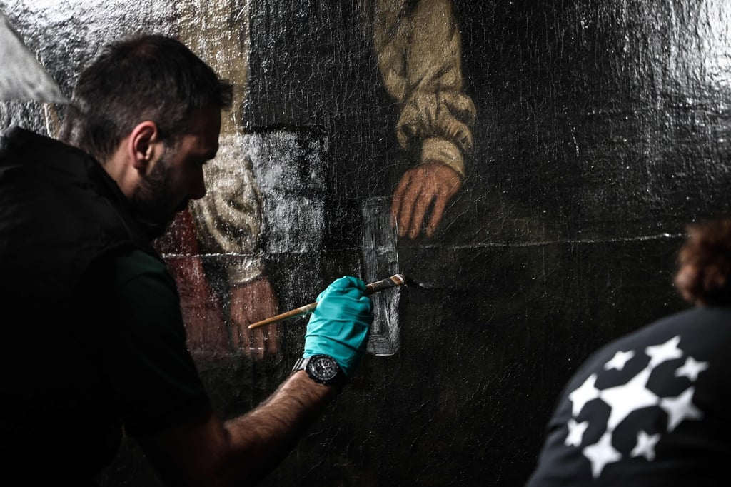 An art restorer works on Gustave Courbet’s painting titled A Burial at Ornans at the Orsay Museum. The painting had not undergone any significant restoration for at least half a century. Photo: AFP