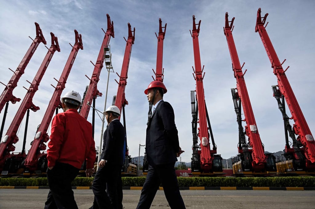 People walk past cranes made by Sany at a factory in Beijing in October 2021. Photo: AFP People walk past cranes made by Sany at a factory in Beijing in October 2021. Photo: AFP