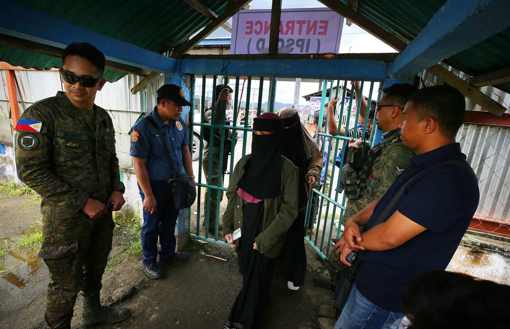 Police and military personnel check voters entering a polling station during national midterm elections in Buadiposo town, Lanao del Sur province, on the southern island of Mindanao on Monday. Photo: AFP Police and military personnel check voters entering a polling station during national midterm elections in Buadiposo town, Lanao del Sur province, on the southern island of Mindanao on Monday. Photo: AFP