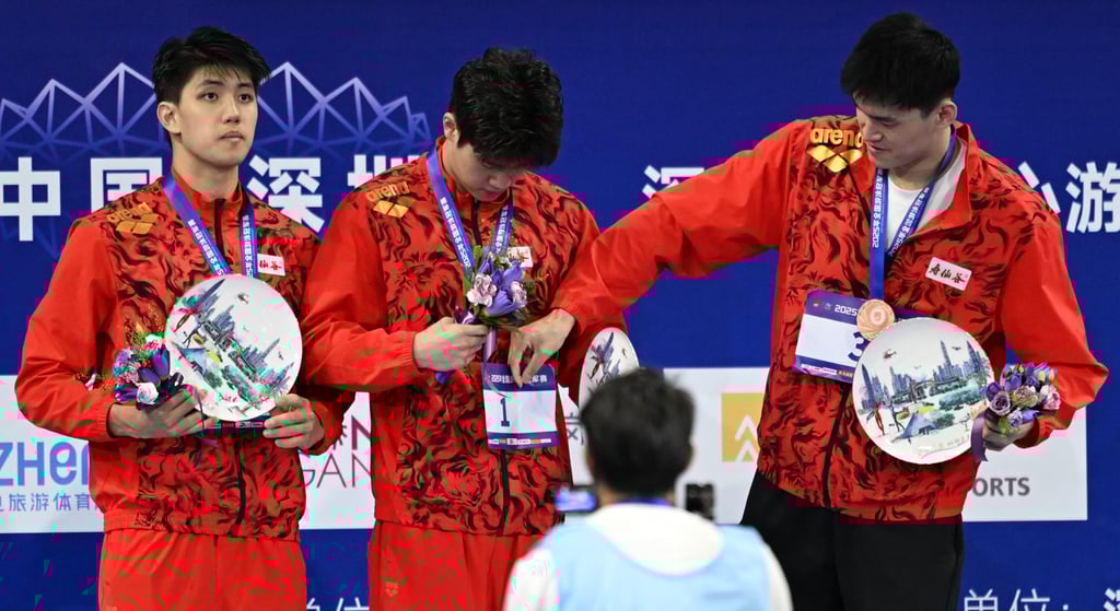 Sun Yang (right) helps Pan Zhanle (centre) with his race number on the podium in Shenzhen. Photo: Xinhua Sun Yang (right) helps Pan Zhanle (centre) with his race number on the podium in Shenzhen. Photo: Xinhua