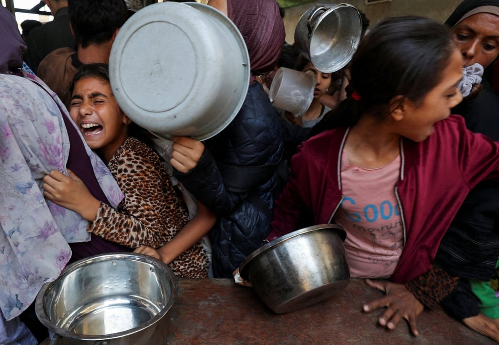 Palestinians wait to receive food cooked by a charity kitchen in Gaza City. Photo: Reuters Palestinians wait to receive food cooked by a charity kitchen in Gaza City. Photo: Reuters