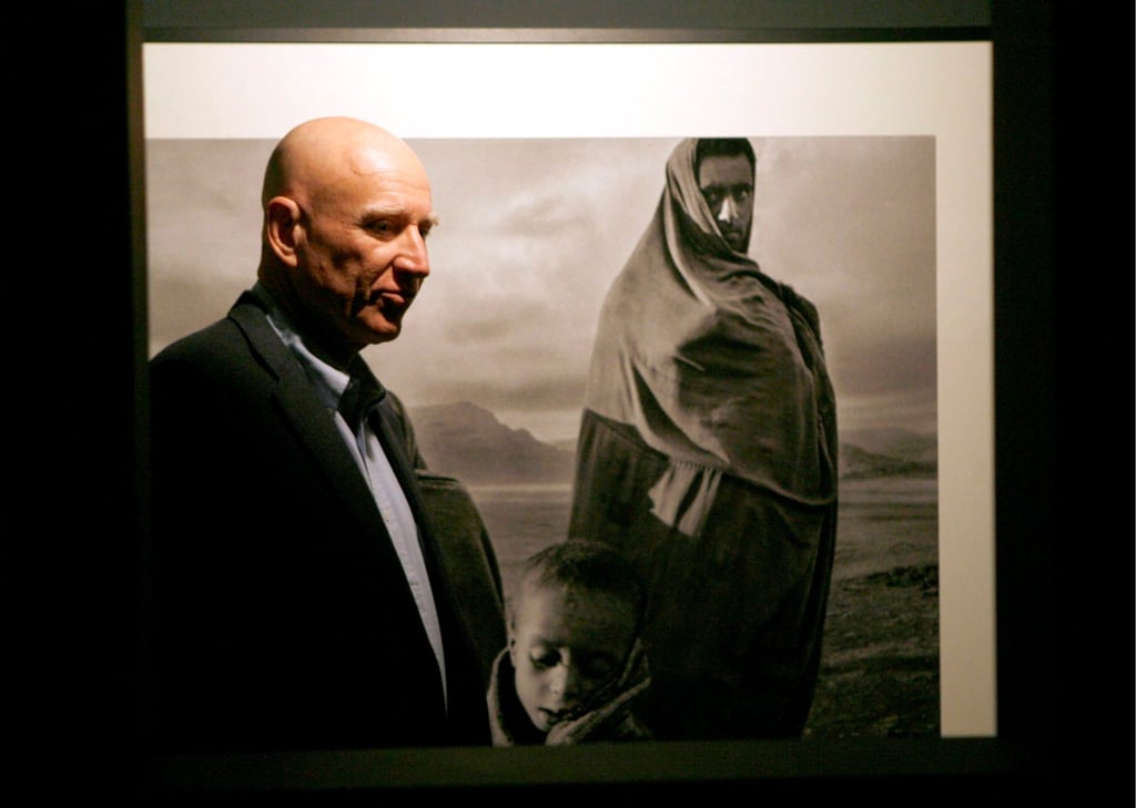 Brazilian photographer Sebastiao Salgado poses in front of his picture, “Refugees in the Korem Camp, Ethiopia, 1984”, for an exhibition in Madrid, Spain, in May 2007. Photo: EPA-EFE
