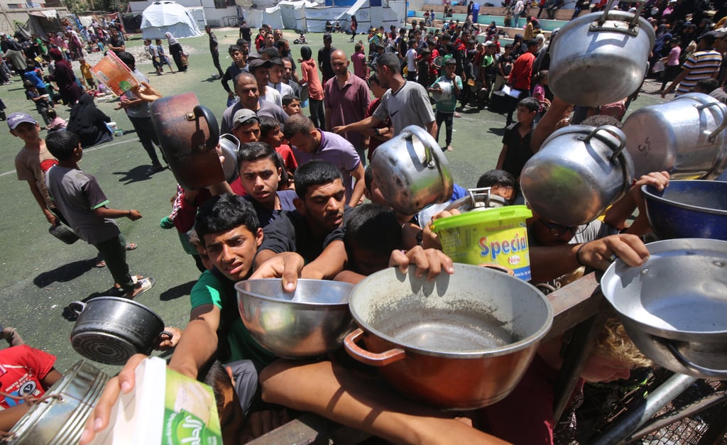 Palestinians wait in long queues to receive pots of food distributed by charitable organizations in Nuseirat Palestinian refugee camp. Photo: dpa Palestinians wait in long queues to receive pots of food distributed by charitable organizations in Nuseirat Palestinian refugee camp. Photo: dpa