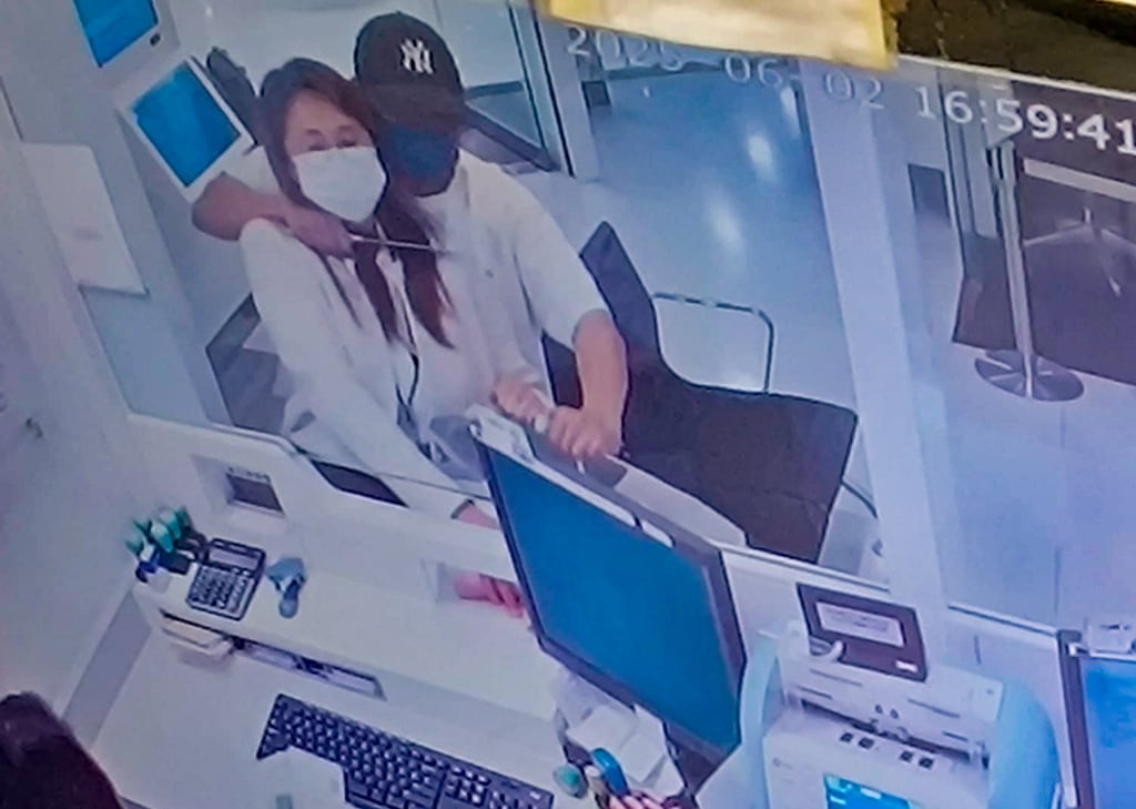 A screen grab of CCTV footage circulating online shows the robber holding a knife at the bank worker’s throat. Photo: Handout A screen grab of CCTV footage circulating online shows the robber holding a knife at the bank worker’s throat. Photo: Handout