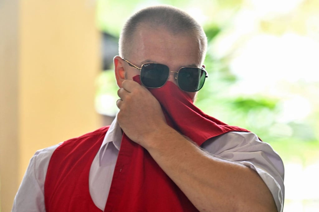 British national Phineas Ambrose Float attempts to hide his face upon arrival at a court in Denpasar, Bali, on Tuesday. Photo: AFP