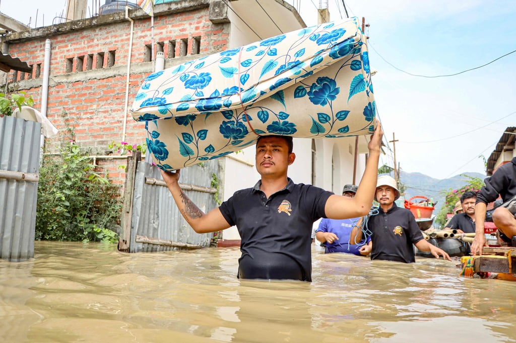 A man carries a mattress as he wades through floodwaters. Photo: AFP A man carries a mattress as he wades through floodwaters. Photo: AFP