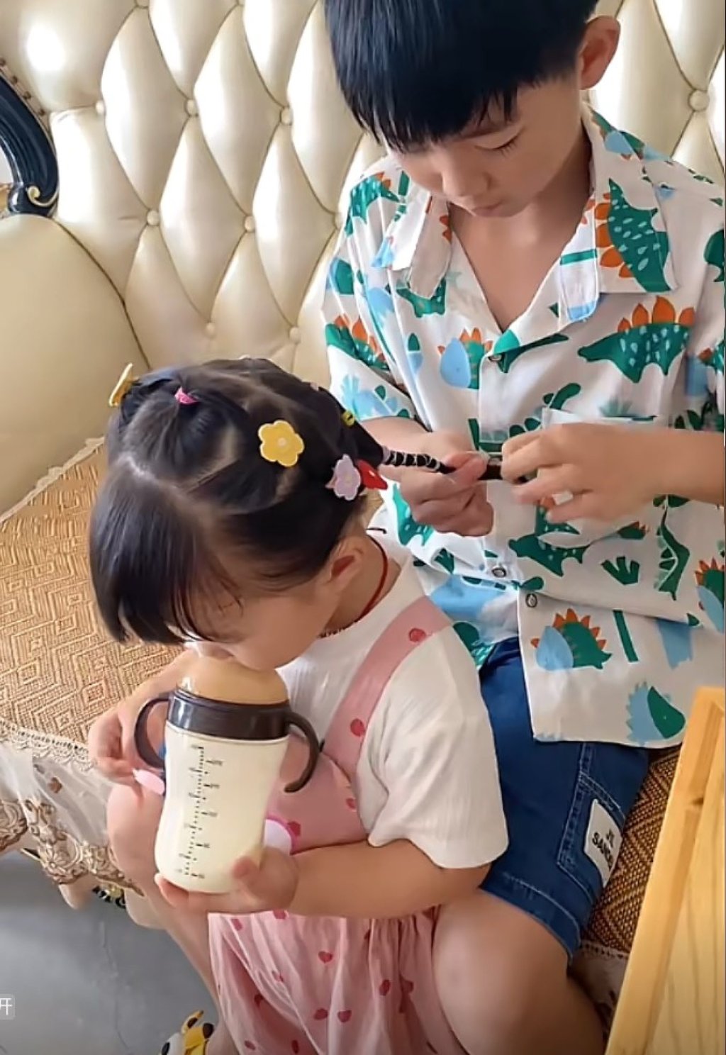 While her brother focuses on braiding, the little girl, often seen sipping milk from a bottle, appears to genuinely enjoy his attentive care. Photo: Douyin While her brother focuses on braiding, the little girl, often seen sipping milk from a bottle, appears to genuinely enjoy his attentive care. Photo: Douyin
