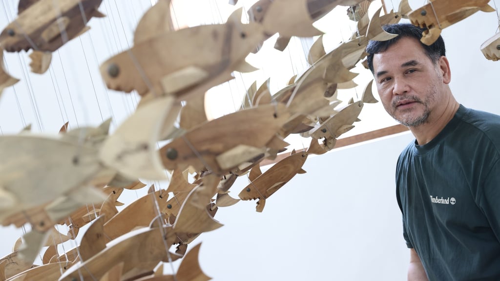 Lam stands with his installation of more than 100 sharks made from salvaged wood at the Tzu Chi Environmental Action Centre in Tai Wai. Photo: K.Y. Cheng Lam stands with his installation of more than 100 sharks made from salvaged wood at the Tzu Chi Environmental Action Centre in Tai Wai. Photo: K.Y. Cheng