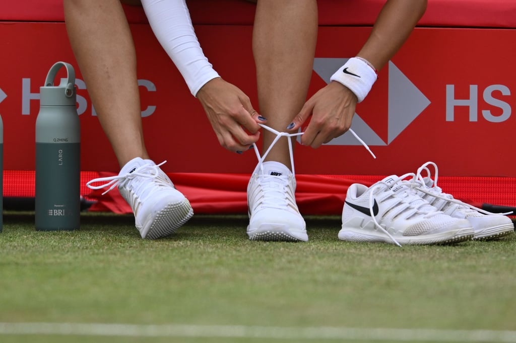 Zheng Qinwen ties the laces of her replacement shoes at Queen’s Club in London. Photo: Xinhua Zheng Qinwen ties the laces of her replacement shoes at Queen’s Club in London. Photo: Xinhua