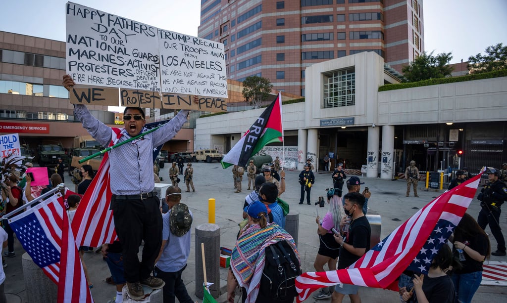 Protesters march past US Marines standing guard outside a federal building in Los Angeles on Sunday. Photo: AP