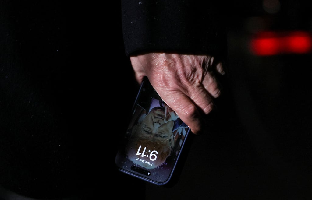 US President Donald Trump holds a mobile phone with his image on it. Photo: Reuters