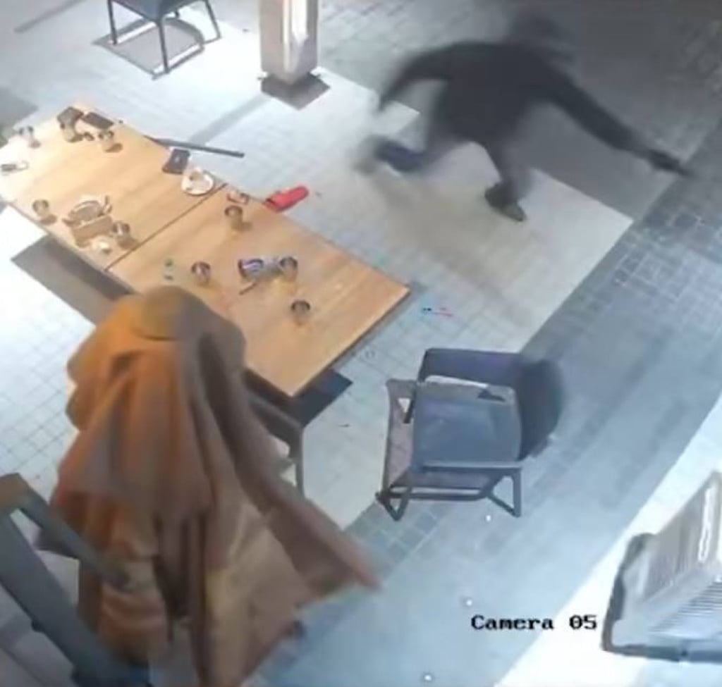 A helmeted gunman is caught on CCTV chasing his victim in a Brickfields restaurant. Photo: Handout A helmeted gunman is caught on CCTV chasing his victim in a Brickfields restaurant. Photo: Handout