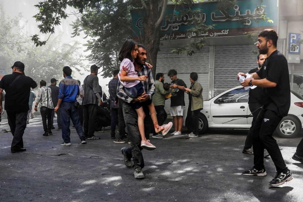 A man carries a wounded girl after an explosion in downtown Tehran amid Israel’s bombing campaign on June 15. Photo: AP/ISNA