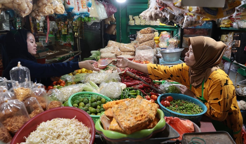 A produce seller serves a customer at a traditional market in Depok, Indonesia. The new stimulus includes rice and staple food aid for 18.3 million poor families. Photo: EPA-EFE A produce seller serves a customer at a traditional market in Depok, Indonesia. The new stimulus includes rice and staple food aid for 18.3 million poor families. Photo: EPA-EFE