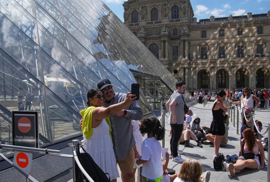 Tourists take a selfie outside the Louvre as they wait for it to open on June 16. Photo: AP