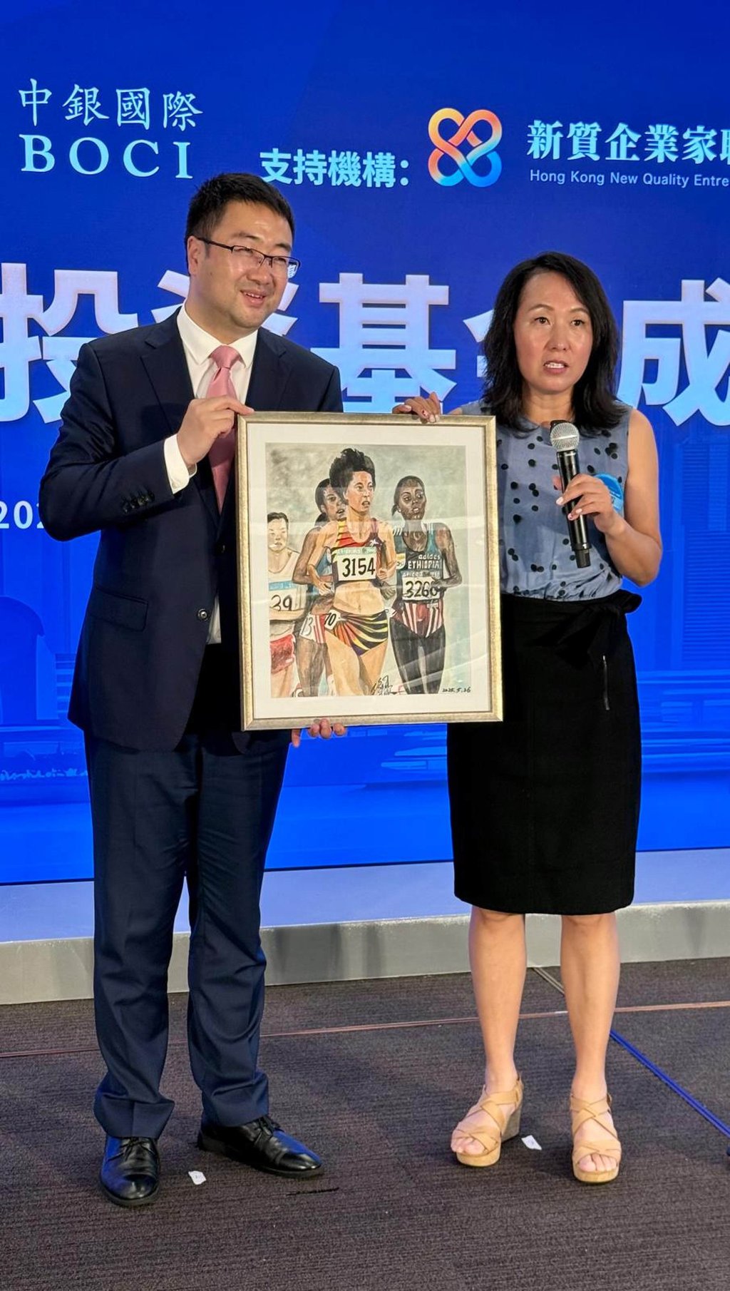Wang Junxia (right) presents a self-painted picture of her Olympic triumph to Jesse Shang. Photo: Mike Chan Wang Junxia (right) presents a self-painted picture of her Olympic triumph to Jesse Shang. Photo: Mike Chan