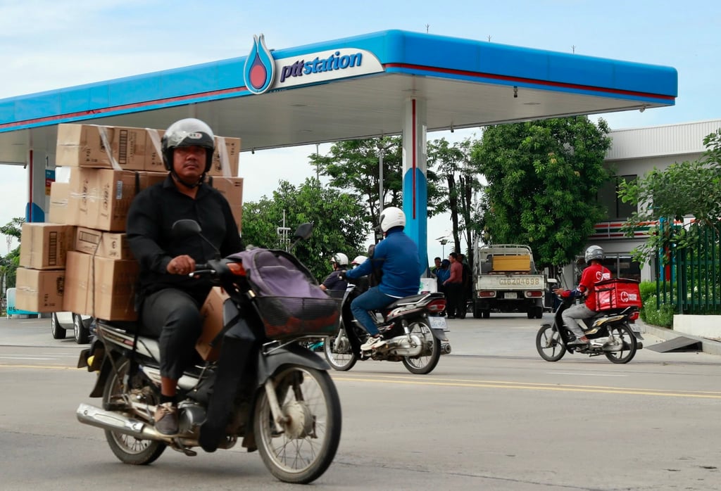 People on motorcycles pass a petrol station in Phnom Penh, Cambodia, on Monday. Photo: EPA-EFE