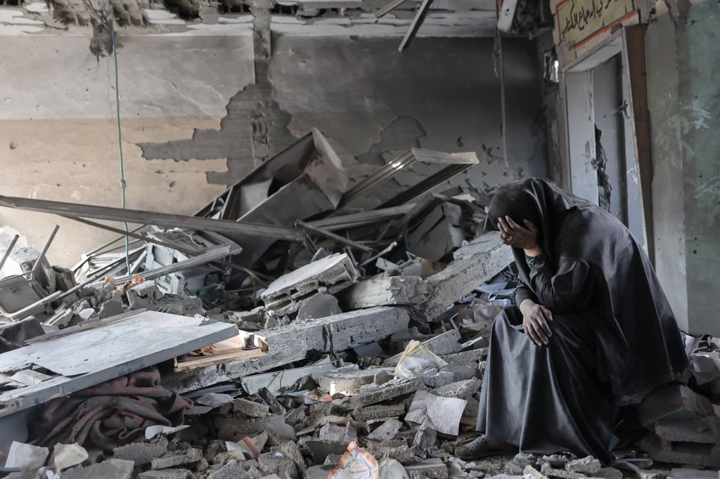 A Palestinian woman sits in the rubble of a school in Gaza City following Israeli strikes. Photo: AFP