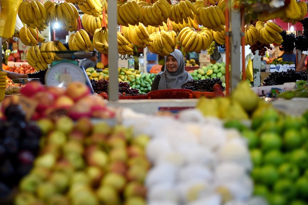 A Malaysian woman shops for fruit at a market in Kuala Lumpur. New taxes on apples and oranges were rolled back soon after their introduction. Photo: AFP A Malaysian woman shops for fruit at a market in Kuala Lumpur. New taxes on apples and oranges were rolled back soon after their introduction. Photo: AFP