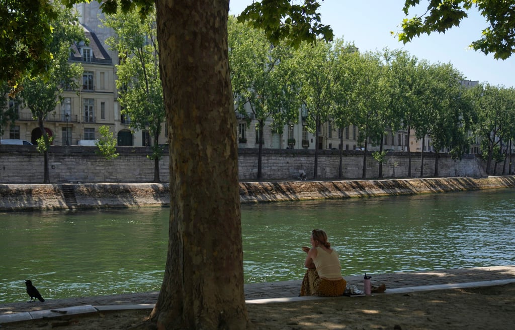 A woman sits on the Seine river banks during a heatwave on Tuesday. Photo: AP