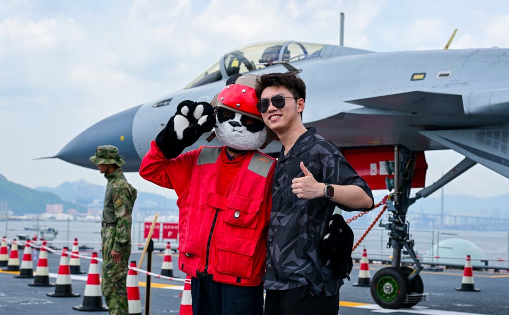 A fighter jet is the backdrop for a visitor’s photo with a crew member. Photo: Xinhua A fighter jet is the backdrop for a visitor’s photo with a crew member. Photo: Xinhua