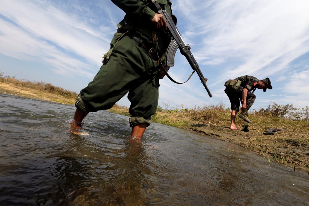 A soldier from the Kachin Independence Army, an ethnic armed group in Myanmar, puts on his shoes as he and his comrade cross a stream. Photo: Reuters