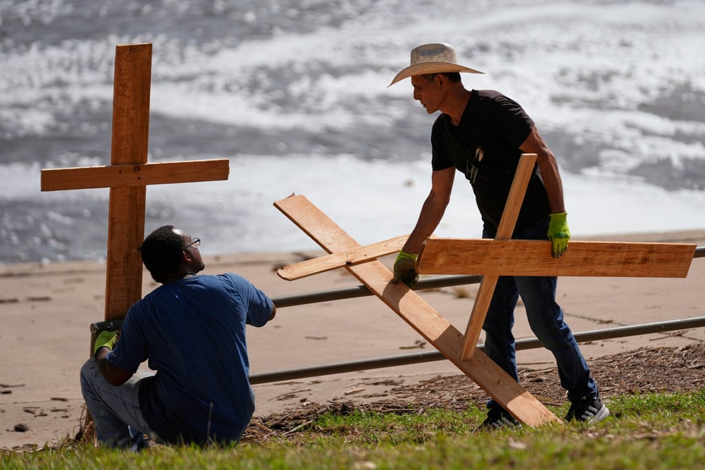 Men place crosses along the Guadalupe River in memory of flood victims. Photo: AP