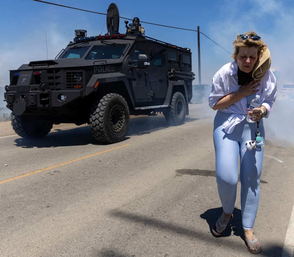 A protester flees as Customs and Border Protection officers fire chemical agents into the crowd during a raid by federal immigration agents at Glass House Farms in Camarillo, California, on Thursday. Photo: AFP