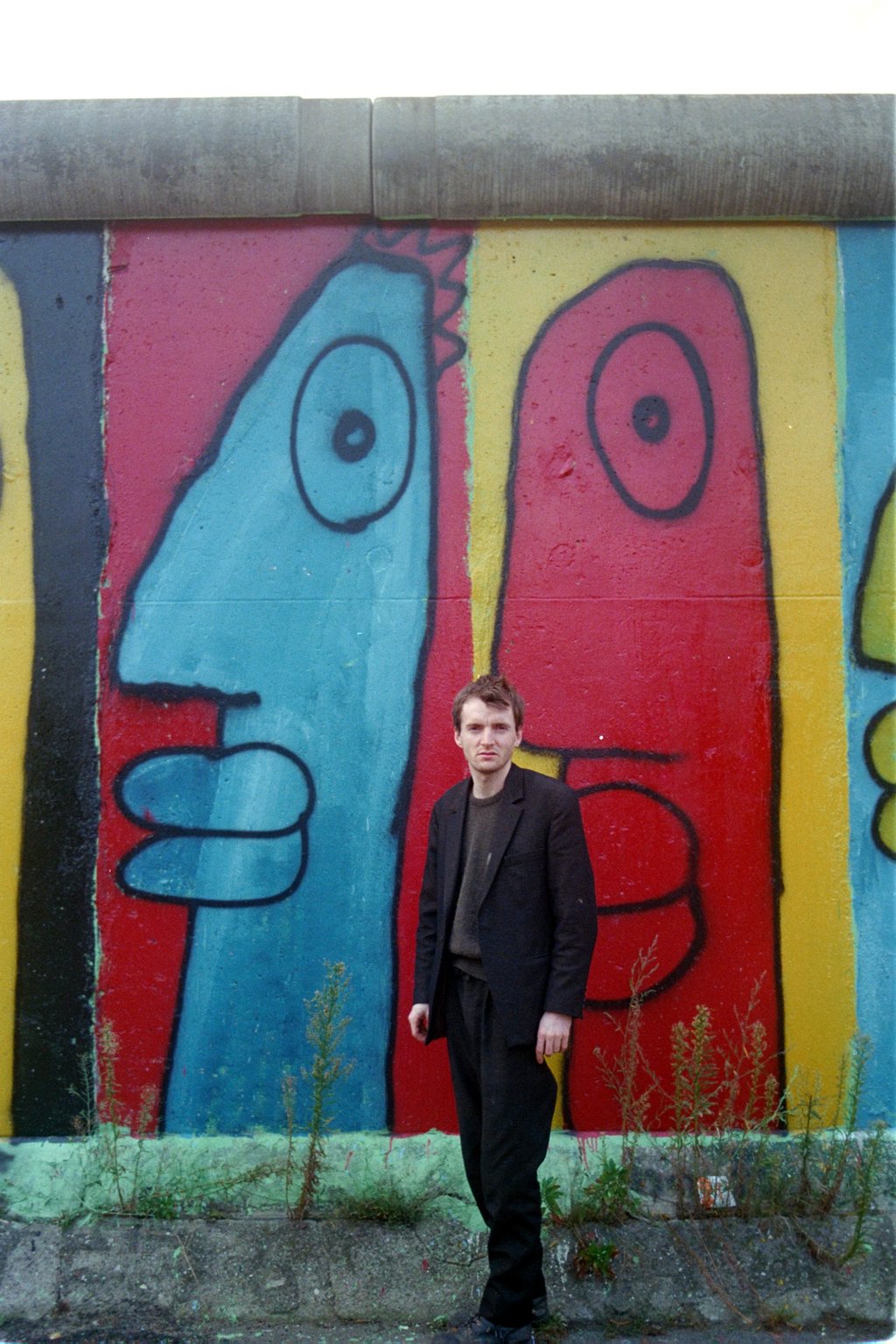 Noir in front of one of his paintings on the Berlin Wall in 1986. Photo: Thierry Noir Studio