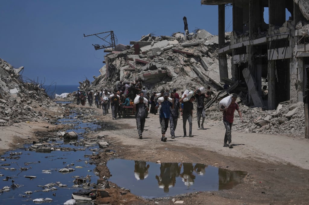 Palestinians carry sacks of flour unloaded from a humanitarian aid convoy. Photo: AP Palestinians carry sacks of flour unloaded from a humanitarian aid convoy. Photo: AP