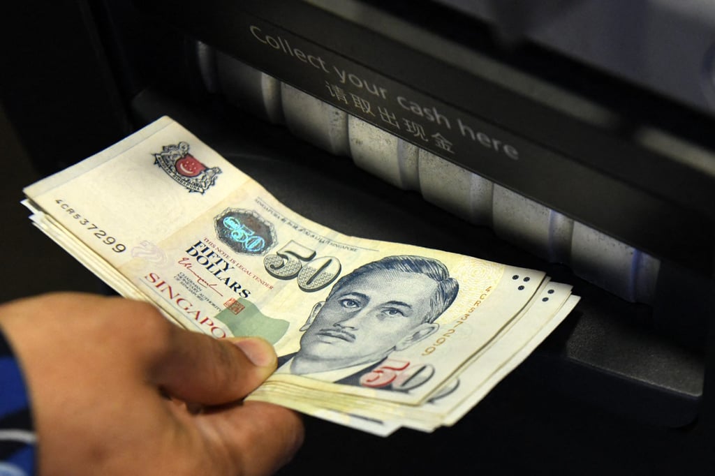 A customer withdraws banknotes from an ATM in Singapore. Financial pressures are among the myriad factors that drive people to suicide, experts say. Photo: AFP