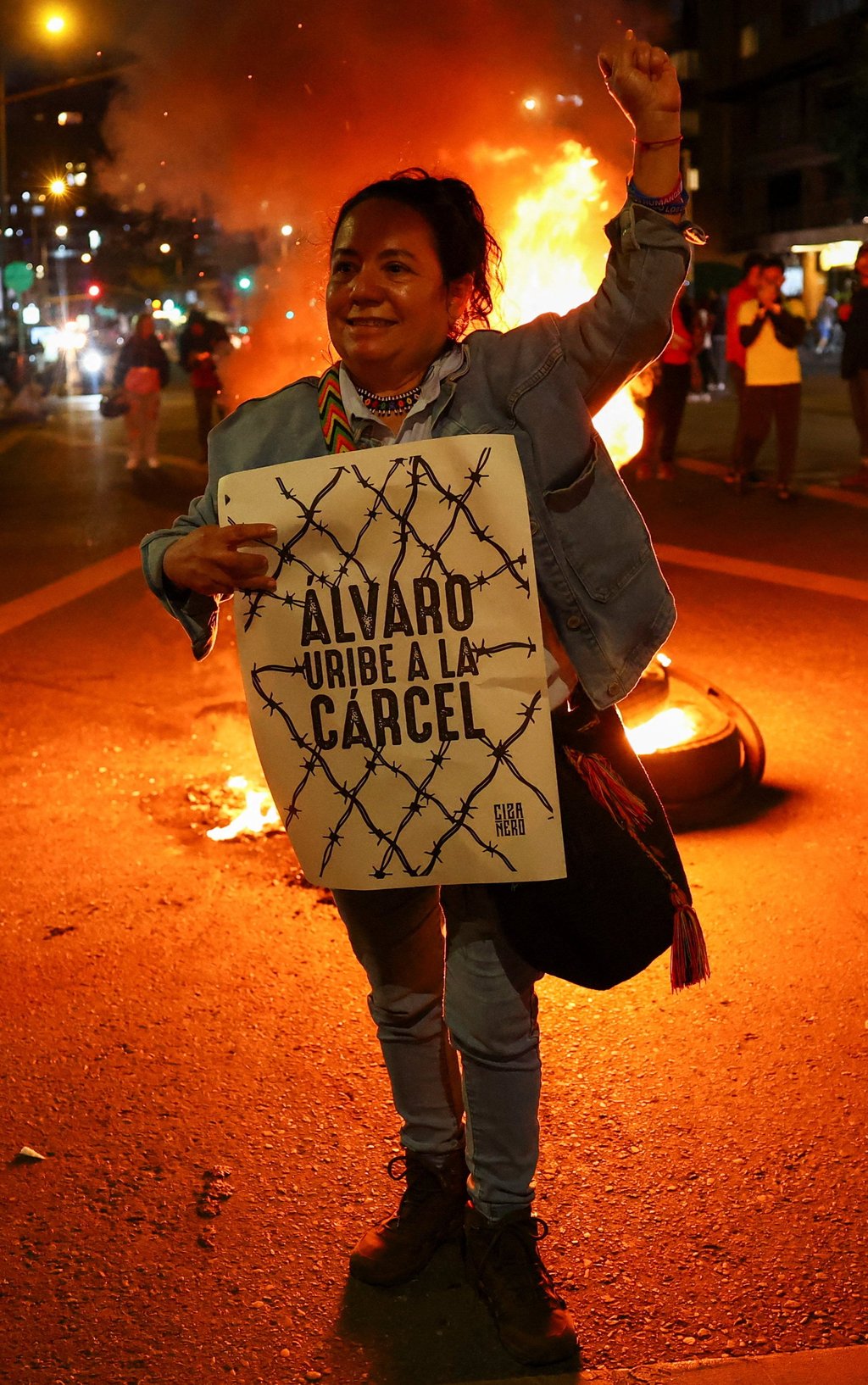 A woman holds a poster that reads “Alvaro Uribe goes to prison” as people gather in Bogota on Monday to celebrate after a judge found former Colombian president Alvaro Uribe guilty of abuse of process and bribery of a public official Photo: Reuters