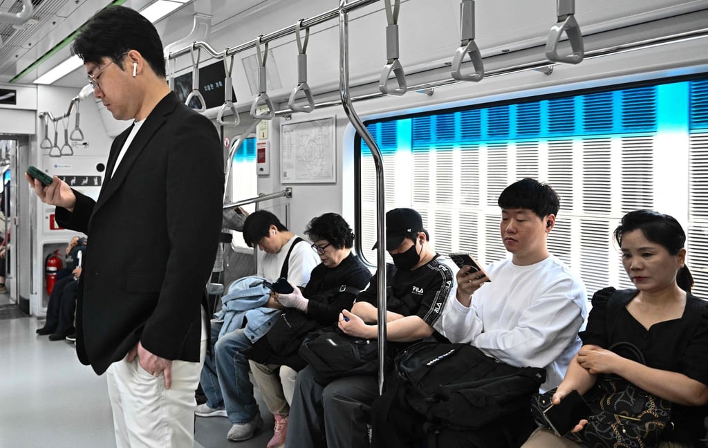 Commuters use their phones on a train in Seoul. Foreign residents have to produce their passport and “alien registration card” for phone plans. Photo: AFP