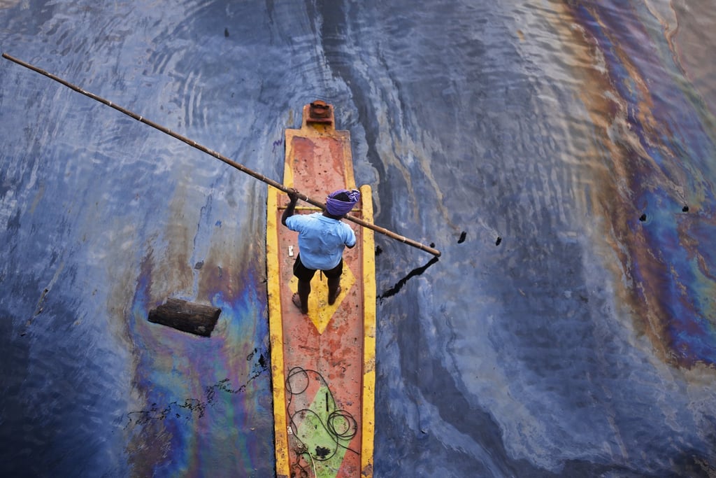 An Indian fisherman sails over the Ennore Creek covered with an oil spill after Cyclone Michaung, in Chennai, India, December 11, 2023. Photo: EPA-EFE