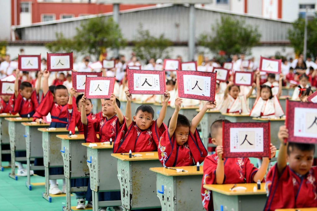 First-grade students hold up cards with the character ‘ren’ meaning ‘person’ during an initiation ceremony to learn about traditional Chinese culture at a primary school in Anlong county, Guizhou province on August 28, 2023. Photo: AFP