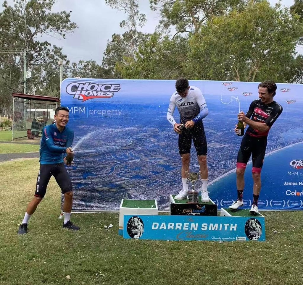 Vincent Lau (left) aims champagne at road race winner Rayann Lacheny and third-placed Australian Ben Carman. Photo: Cycling Association of Hong Kong, China