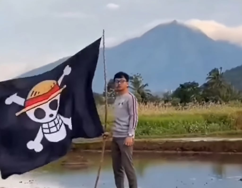 A man in Indonesia holds a One Piece flag with an active volcano in the background. Photo: Facebook