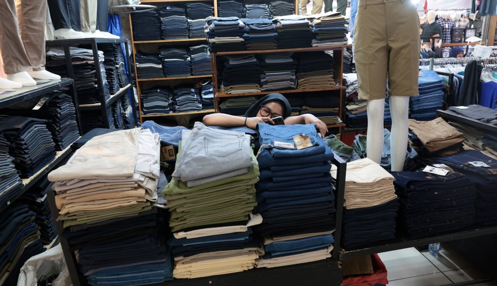 A saleswoman checks her phone in a quiet shopping mall in Depok, Indonesia, on Tuesday. Photo: EPA