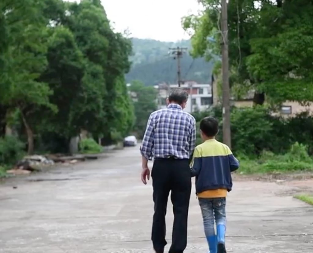Huang Meisheng walks and chats with one of the children he has taken under his wing. Photo: Xinhua Huang Meisheng walks and chats with one of the children he has taken under his wing. Photo: Xinhua