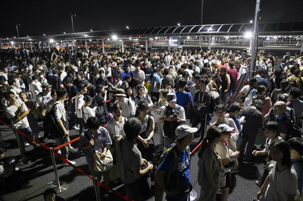 Visitors wait in line for taxis in front of the entrance gate of the World Exposition in Osaka on Wednesday night, after services were suspended on the Osaka Metro’s Chuo Line, which offers sole direct train access from the city centre to the expo site on Yumeshima island. Photo: Kyodo