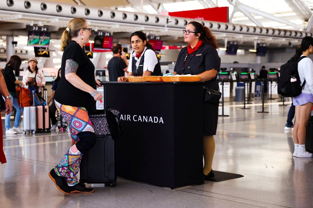 Air Canada workers speak with a passenger at Toronto Pearson International Airport in Mississauga, Ontario, on Friday. Photo: Reuters.
