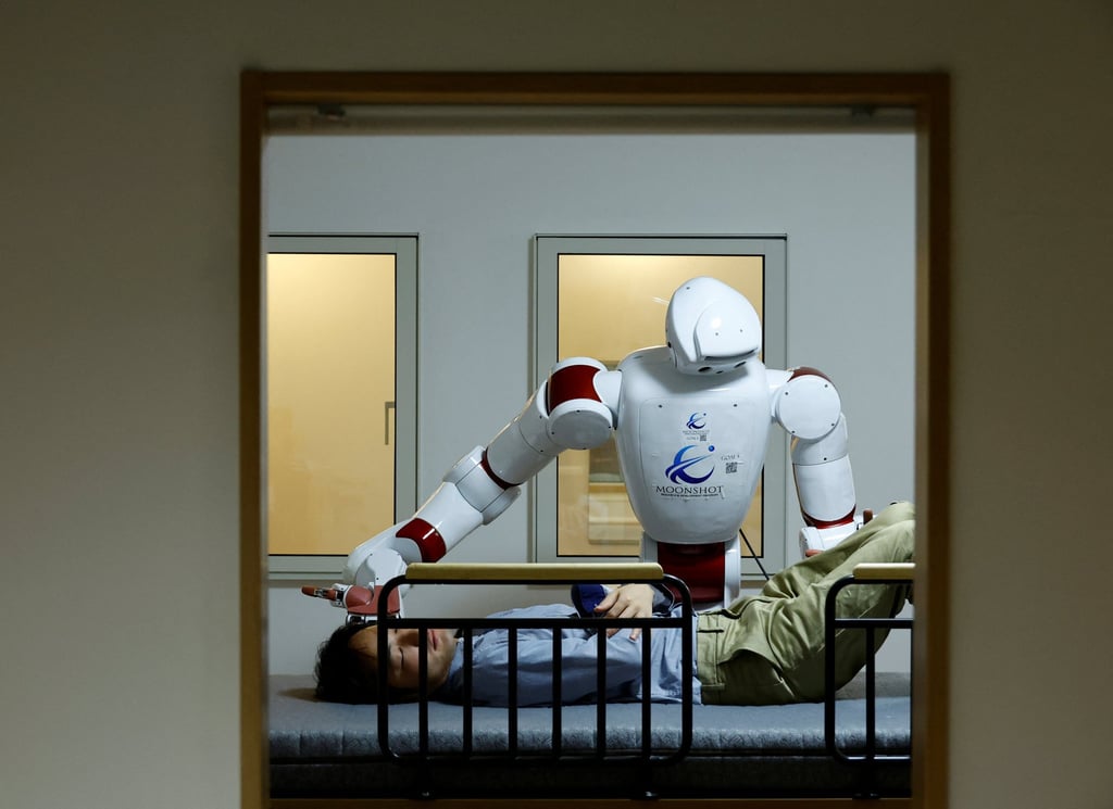 AIREC, an AI-driven humanoid robot, demonstrates a manoeuvre for changing linen or preventing bedsores with a researcher at Waseda University’s laboratory in Tokyo. Japan is seeking ways to use AI to maintain economic stability while coping with an ageing workforce. Photo: Reuters