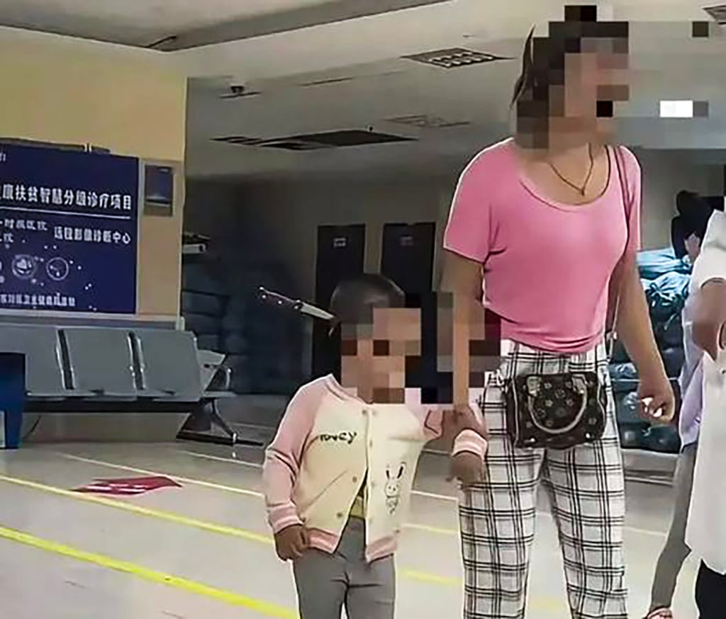Hu walks into the hospital with her toddler daughter, who has a fruit knife stuck into the side of her head. Photo: Weibo Hu walks into the hospital with her toddler daughter, who has a fruit knife stuck into the side of her head. Photo: Weibo